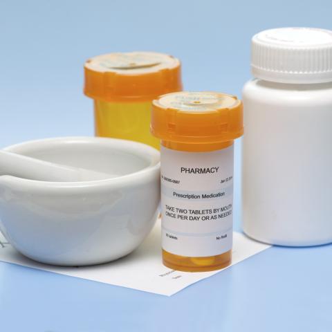 A mortar and pestle near pill bottles